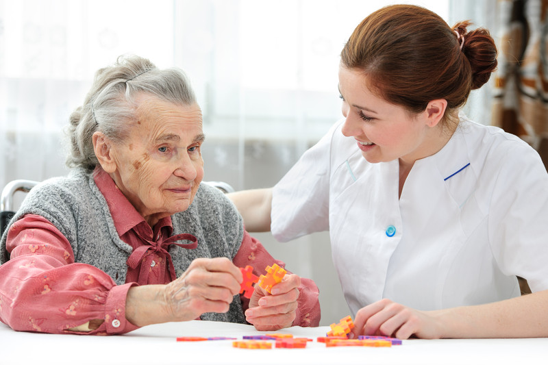 Senior woman seated at table with caregiver | Comfort Keepers Calgary | BLOG POST | Senior Care Services