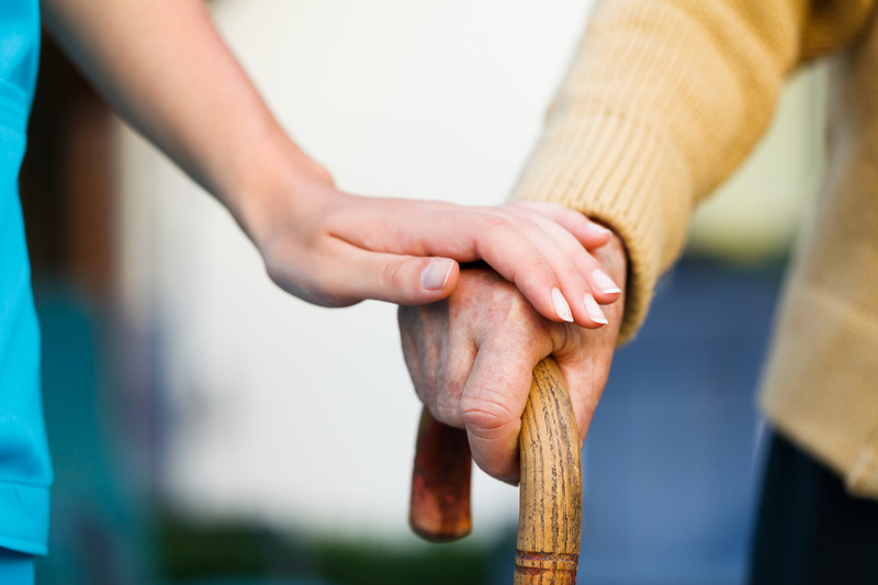 Senior with hand on cane, caregiver hand a top | Comfort Keepers Calgary | BLOG POST | Senior Fall Prevention