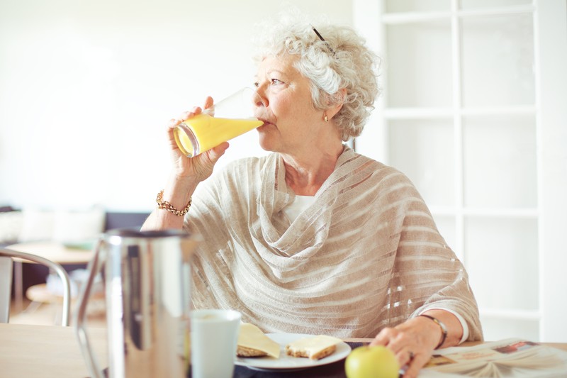 Senior woman drinking orange juice | Comfort Keepers Calgary | BLOG POST | Healthy Aging Tips For Seniors
