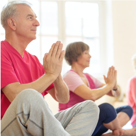 Seniors sitting crossed legged with prayer hands positioned at their chest | Comfort Keepers Calgary | Low Impact Exercise for Seniors | BLOG POST