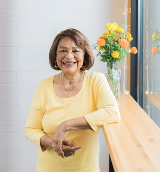Senior woman standing by window and smiling | Comfort Keepers Calgary | Advice and Wellness Tips Regarding COVID-19 | BLOG POST