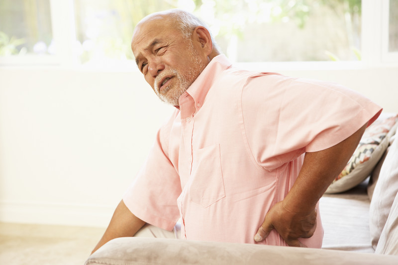 Senior Malle holding his lower back seemingly in pain | Comfort Keepers Calgary | BLOG POST | Common Health Issues for Seniors