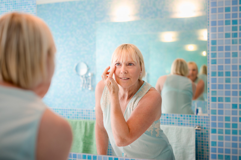 Senior Woman looking in bathroom mirror | Comfort Keepers Calgary | BLOG POST | Age-Related Macular Degeneration