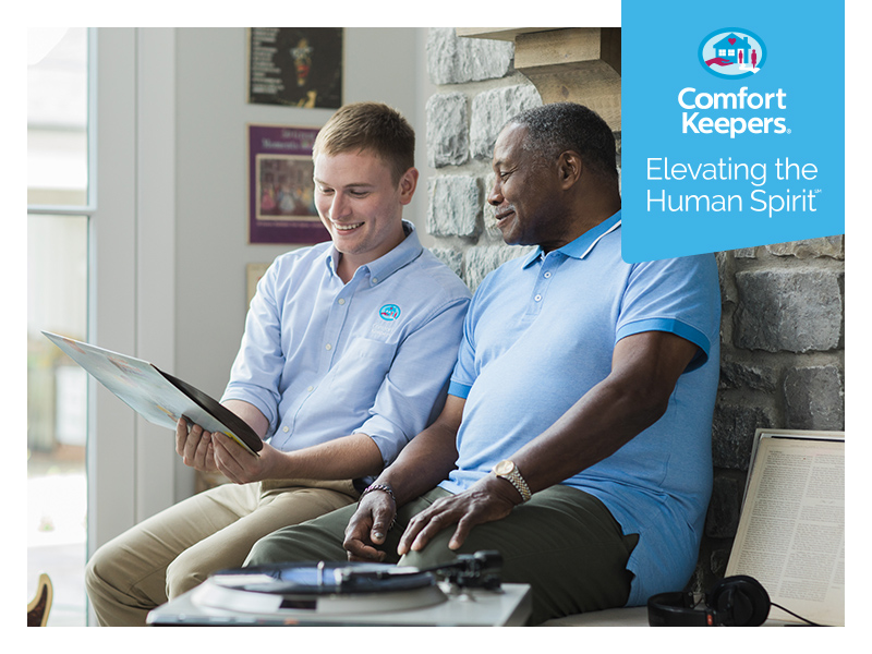 Male sitting with caregiver looking at technology | Comfort Keepers Calgary | BLOG POST | At Home Care Services for Seniors Recovering from Heart Attack