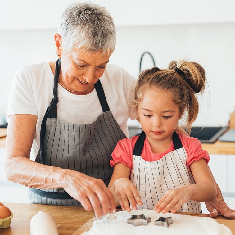 Grandmother and grnaddaughter wearing aprons and baking | Comfort Keepers Calgary | BLOG POST | Considering Respite Care for the Holidays