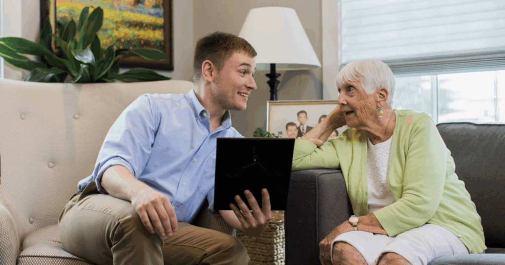 Senior seated with caregiver, looking at photograph in frame