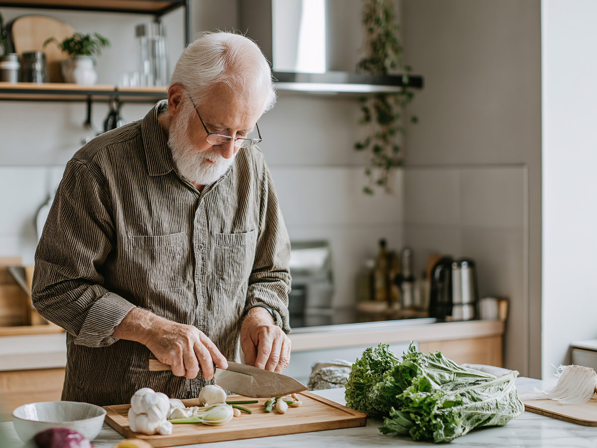 A senior male chopping with a knife in the kitchen | Edmonton Seniors and Kitchen Safety: Tips for the Heart of the Home | Comfort Keepers Edmonton