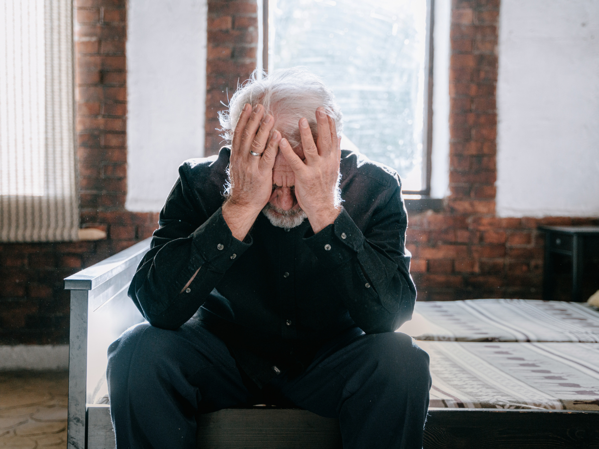 A senior male sits with his head resting in his hands | Elderly Home Care and Depression in Edmonton's Seniors | Comfort Keepers Edmonton