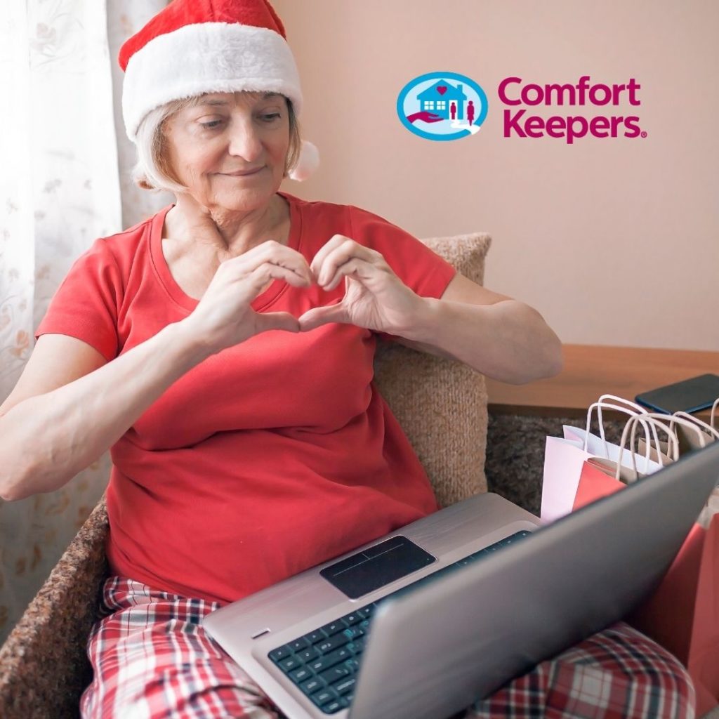 Senior woman shaping her hands into a heart with a computer on her lap. Connecting with family online during the holiday