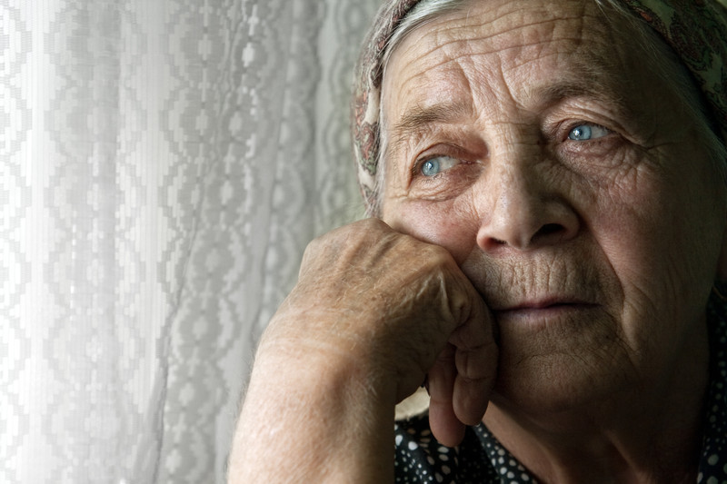 Seniors with Depression | Comfort Keepers Edmonton | BLOG POST | Senior women leaning on hand gazing out window seemingly depressed