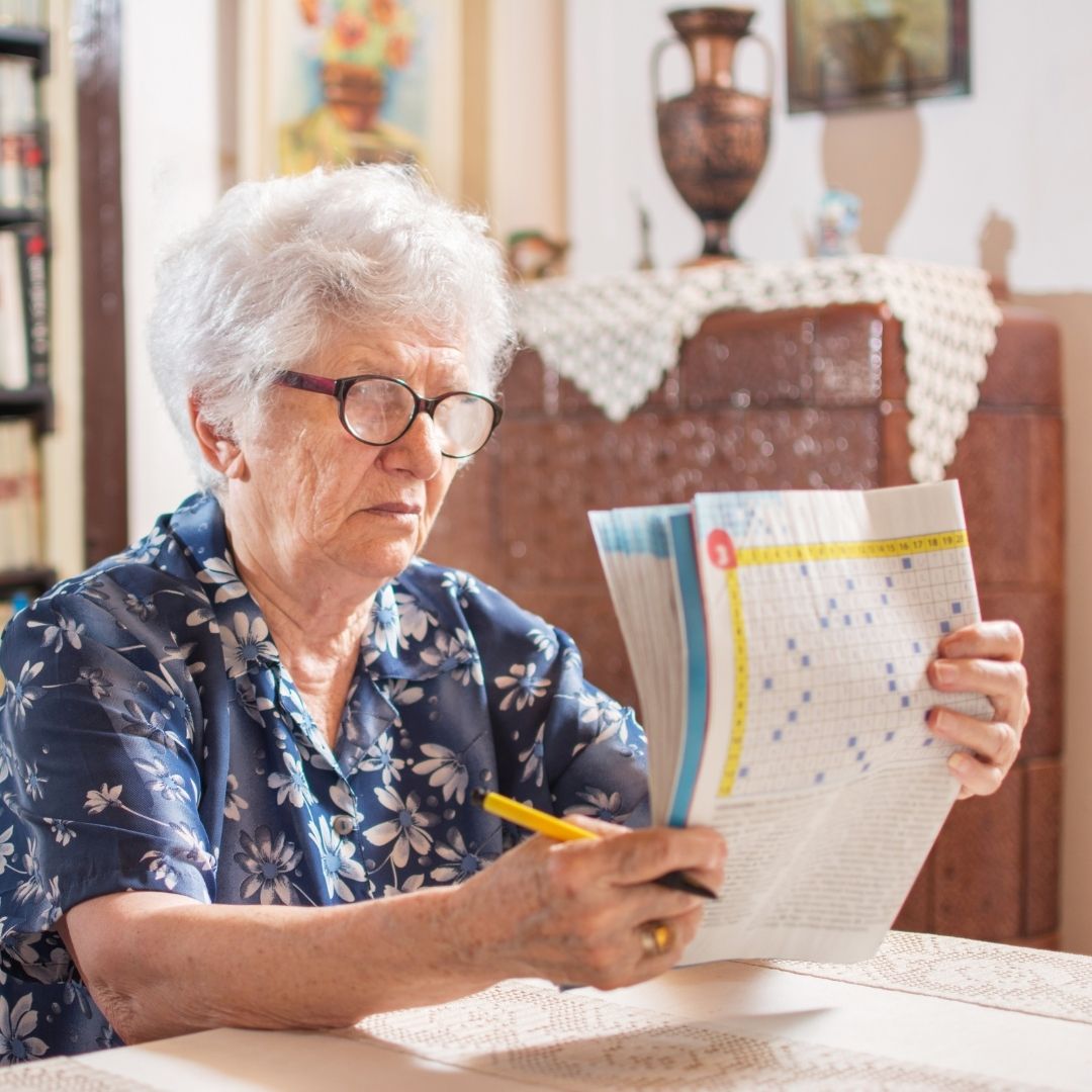 Senior seated at table reviewing a crossword