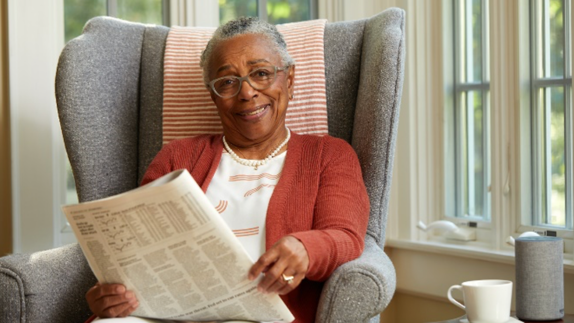 Senior woman seated on armchair holding a newspaper | Comfort Keepers Georgian Triangle | BLOG POST | COVID:19 Help for Seniors