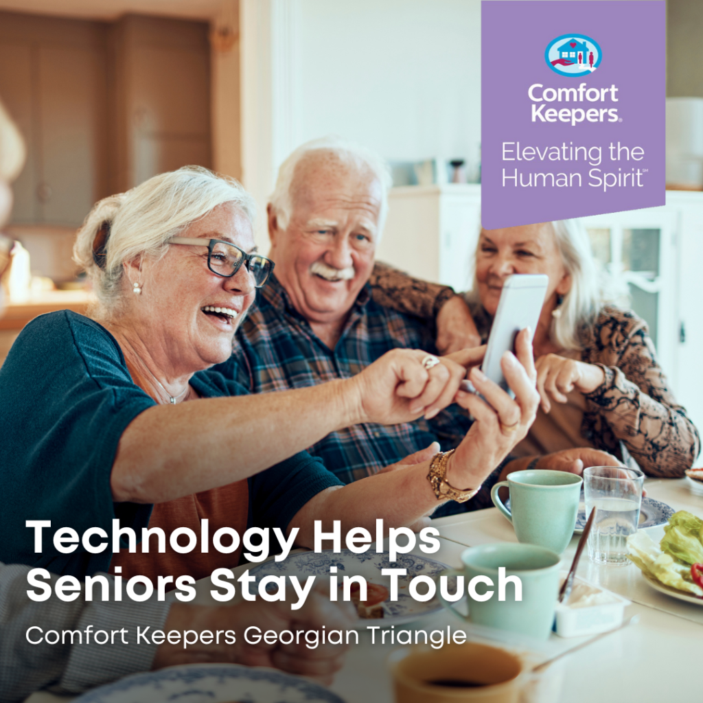 Seniors seated at table enjoy their cell phone | Technology Helps Seniors Stay in Touch - Comfort Keepers Georgian Triangle