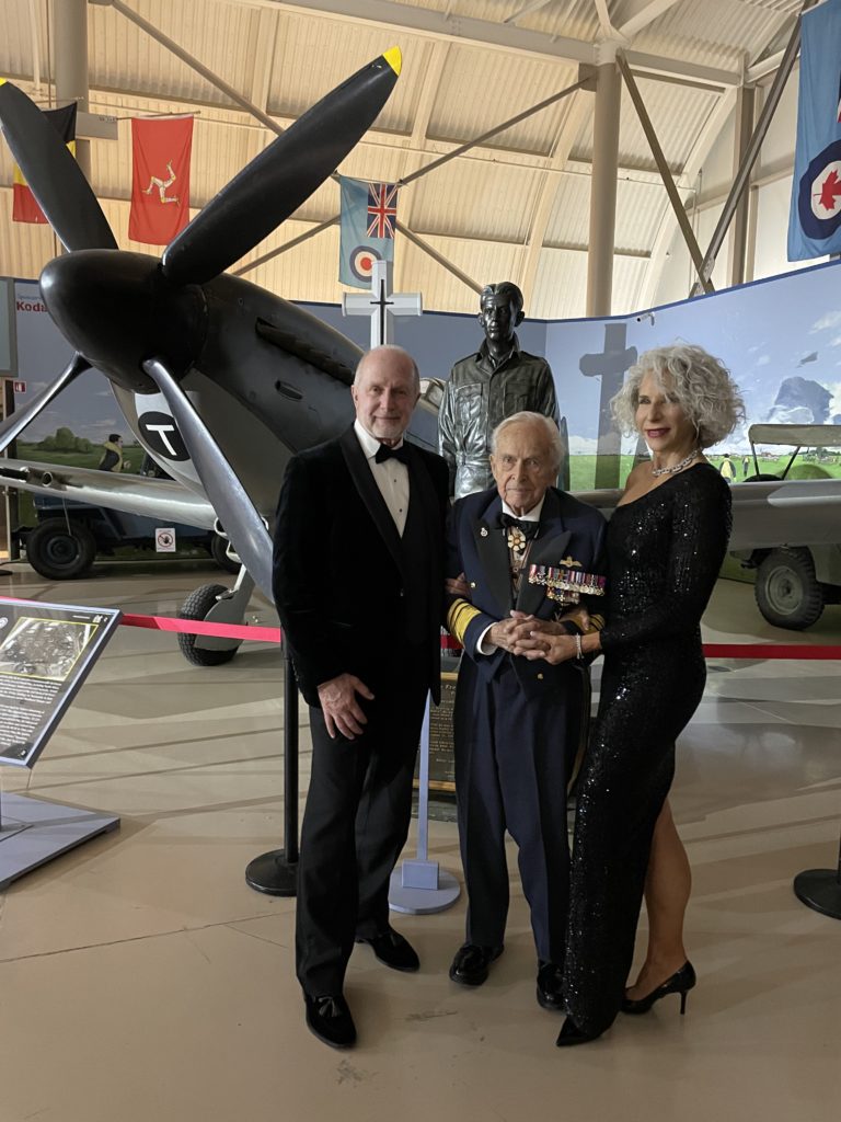 Blaine Bell (owner of Comfort Keepers Georgian Triangle) with his wife Elizabeth and Lieutenant General (Ret.) Richard Rohmer standing in front of the Supermarine Spitfire fighter at the 50th Anniversary of the Canadian Warplane Heritage Museum in Hamilton, Ontario.