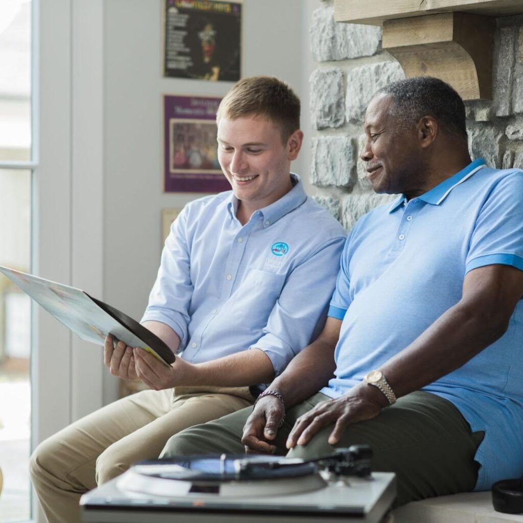 Young caregiver sharing a musical moment with an older adult at home.