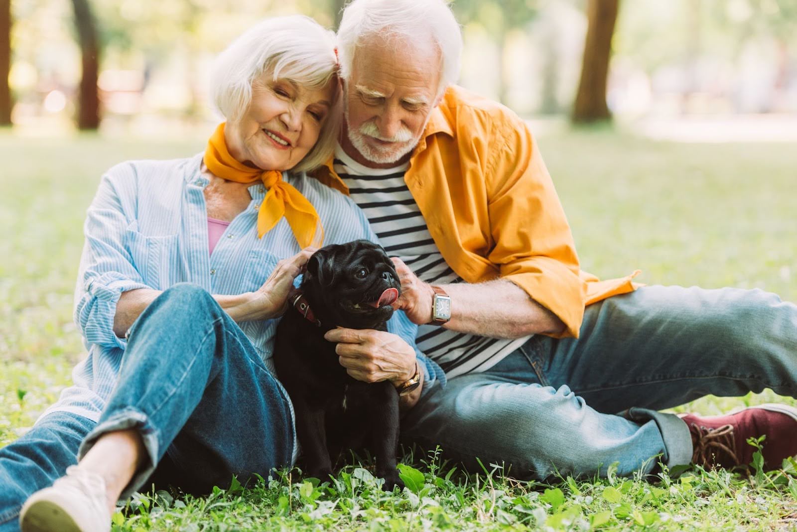 Smiling senior woman lying outdoors with her dog in Guelph park