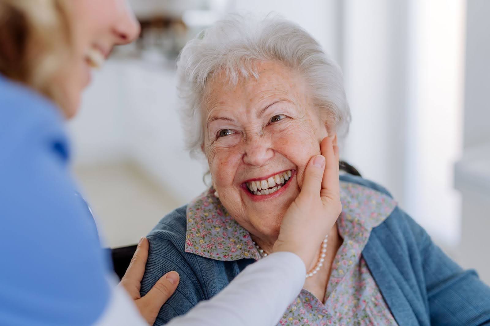 Smiling senior woman receiving gentle care from caregiver in Guelph home