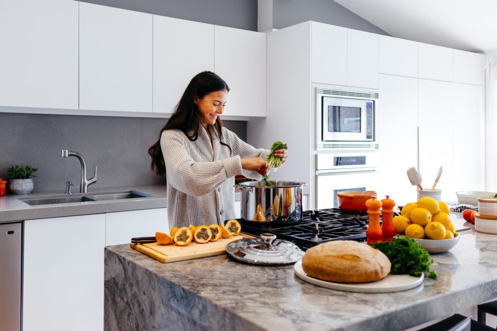 A young lady preparing a meal in a kitchen; this eases the challenge of having to cook for oneself in retirement