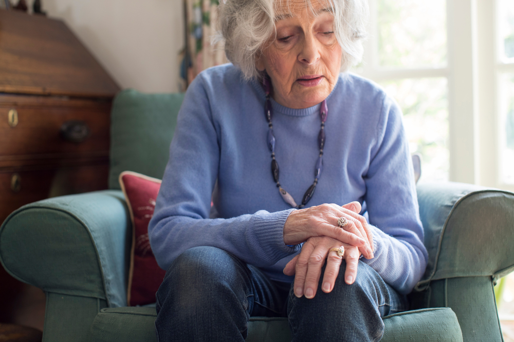 Senior Woman sitting and looking down at her wrist | BLOG: 5 Tips for helping a Loved One with Parkinson's Disease