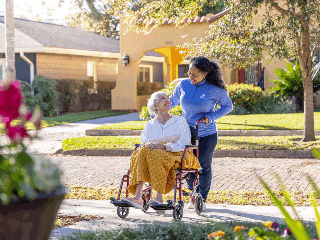 A senior woman in a wheelchair is being pushed by her caregiver | Companionship vs Homemaking Care for Seniors | Comfort Keepers North and West Vancouver