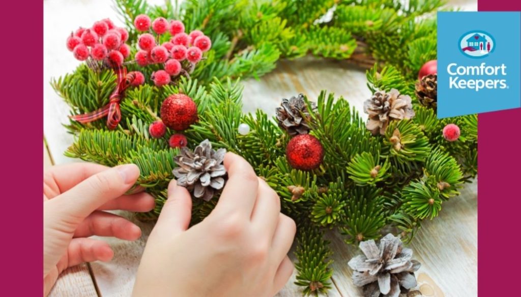 Two hands making a Christmas Wreath with the Comfort Keepers logo in right hand corner