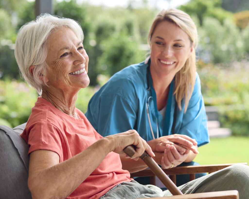 A professional caregiver assisting a senior woman with mobility challenges outdoors, providing home care for Parkinson’s in Ottawa.