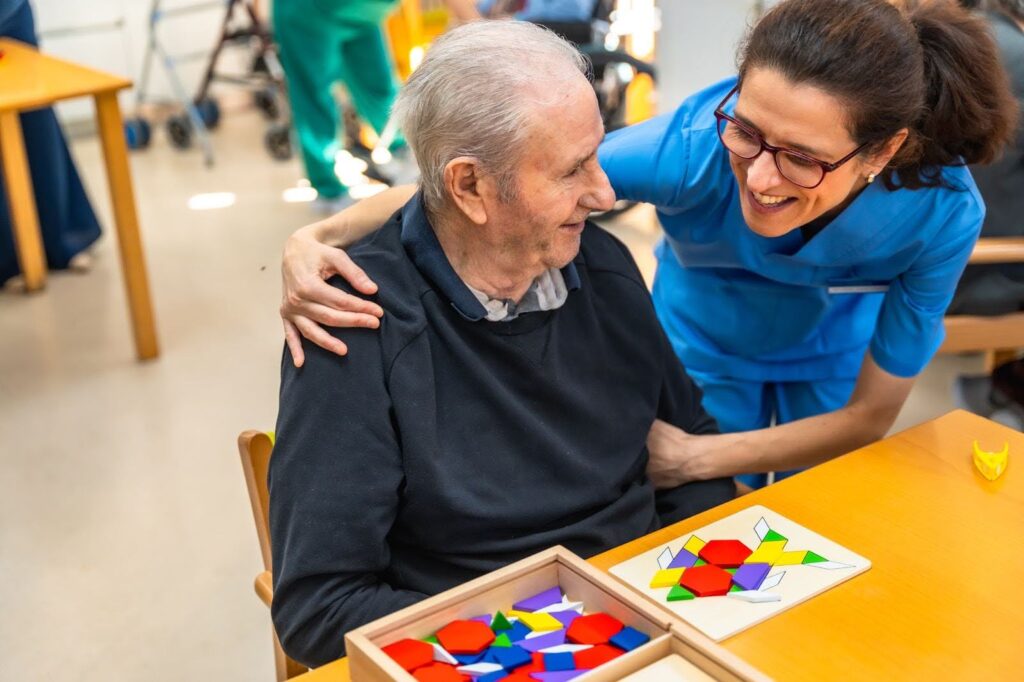 Elderly man smiling while playing a board game with a professional caregiver in Ottawa home care setting.