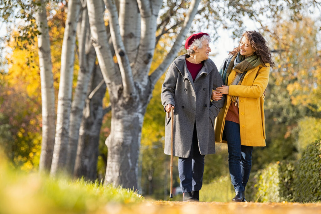 older woman and a younger woman walking side-by-side outdoors on crisp autumn day