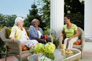 Maria, the Comfort keepers caregiver, sitting on the terrace and having a delightful conversation with two elderly women.
