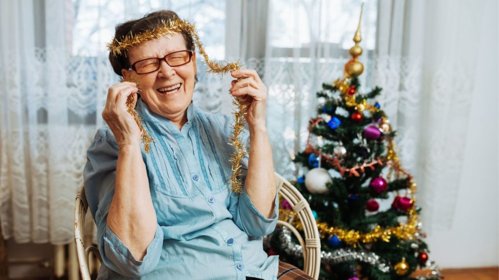 Senior woman laughing with tinsel on her head during the holidays 