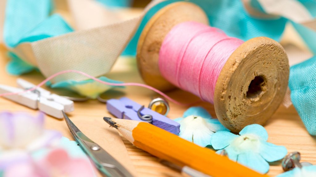 Scrapbooking materials including thread, pencils and decoupage on a table