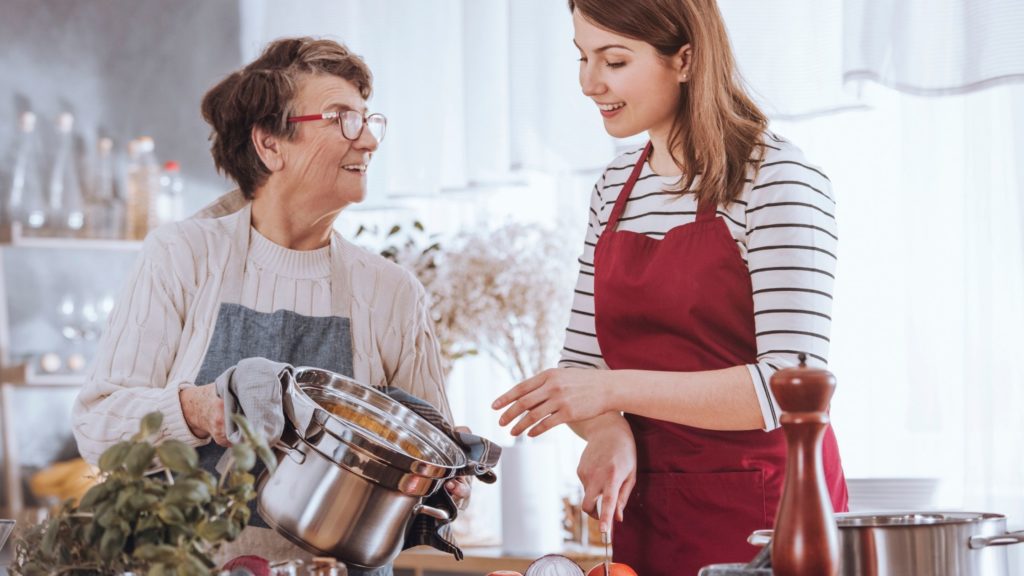 Senior with diabetes and adult daughter cooking in kitchen 