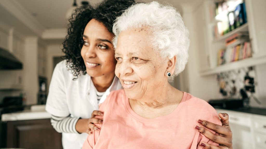 Senior mother with adult daughter smiling in a home setting