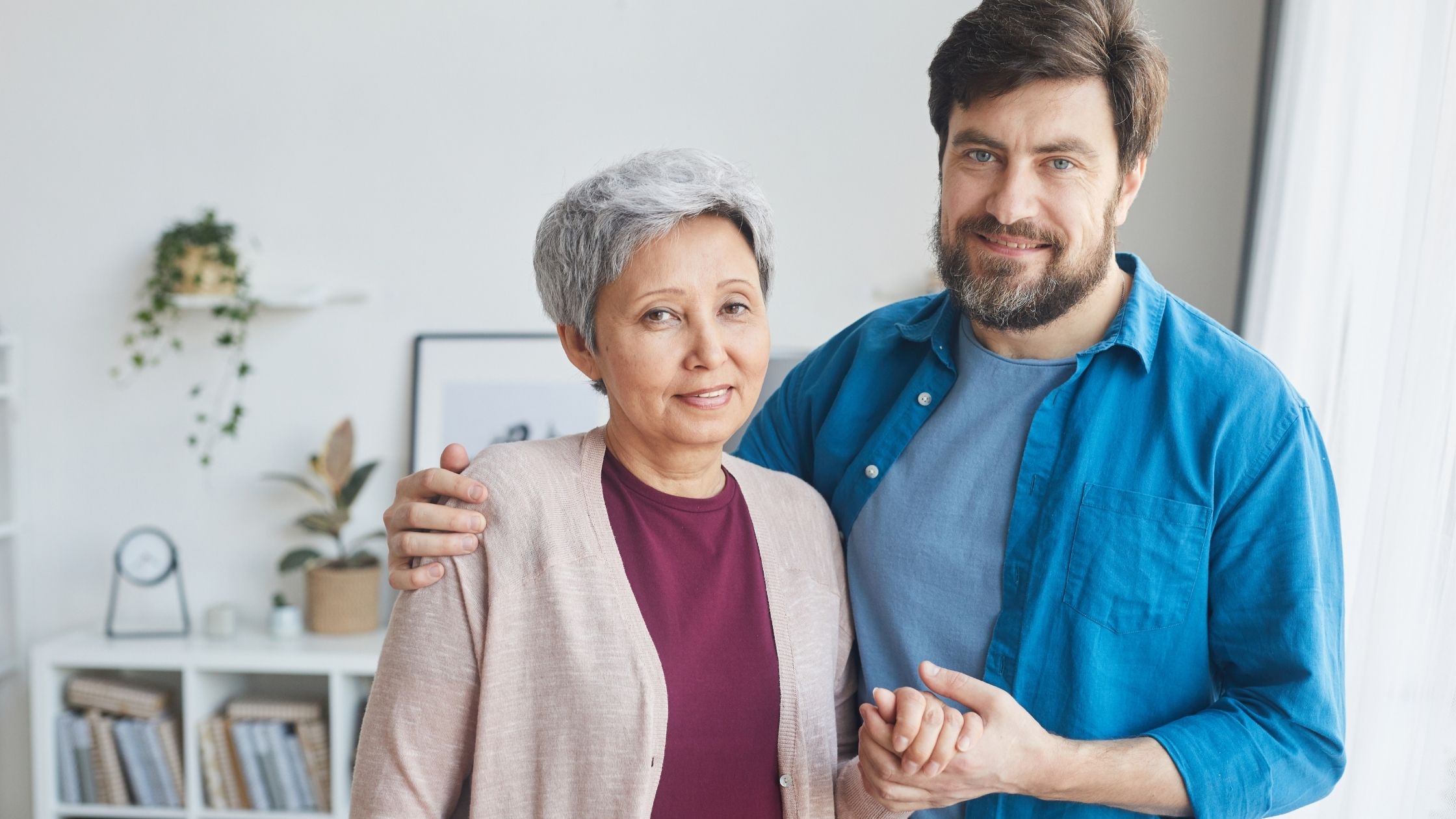 Adult son and senior mother standing shoulder to shoulder