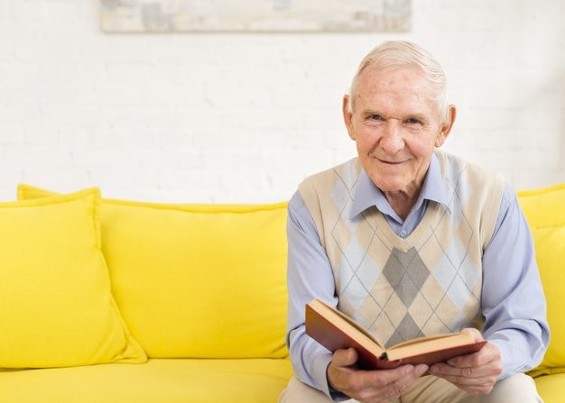 Senior man in his home reading a book