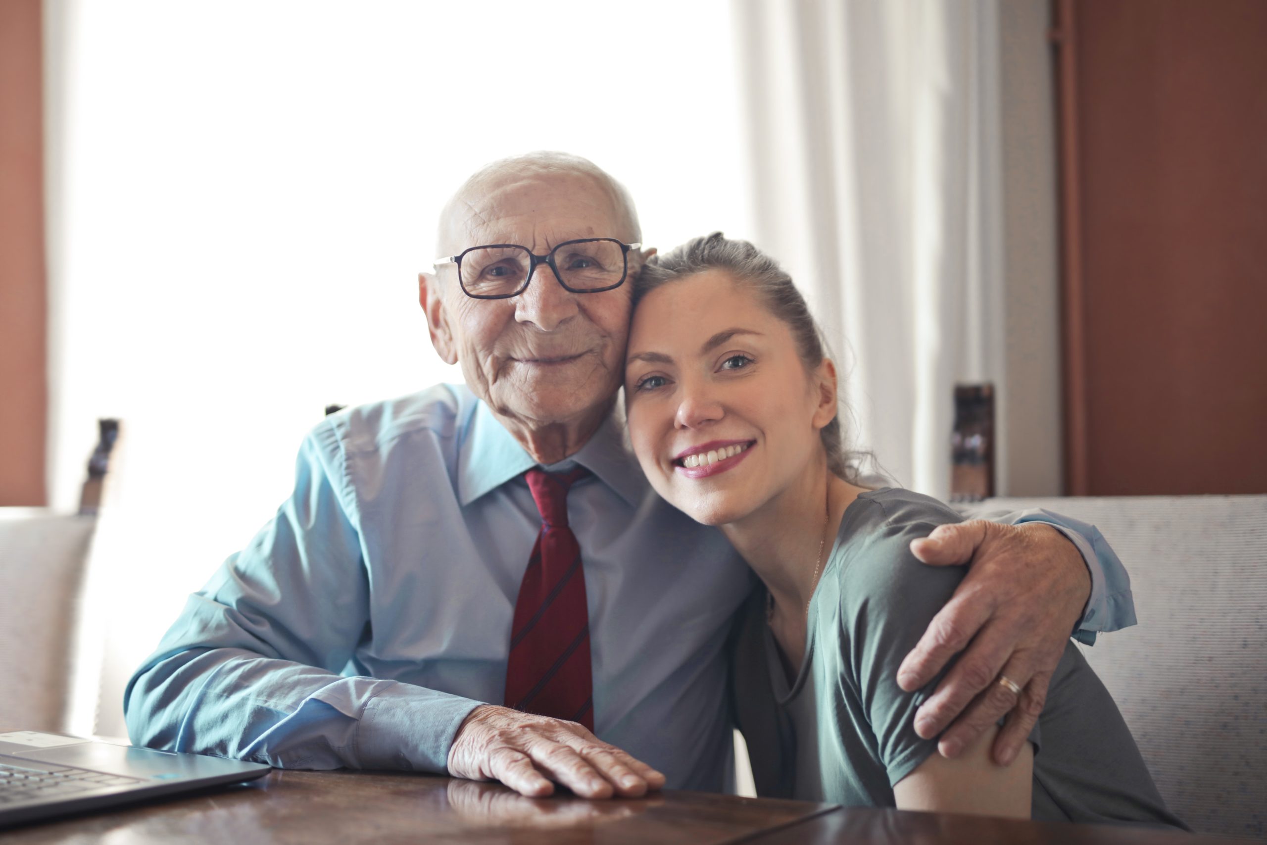 Senior man at home with younger female family member looking at camera