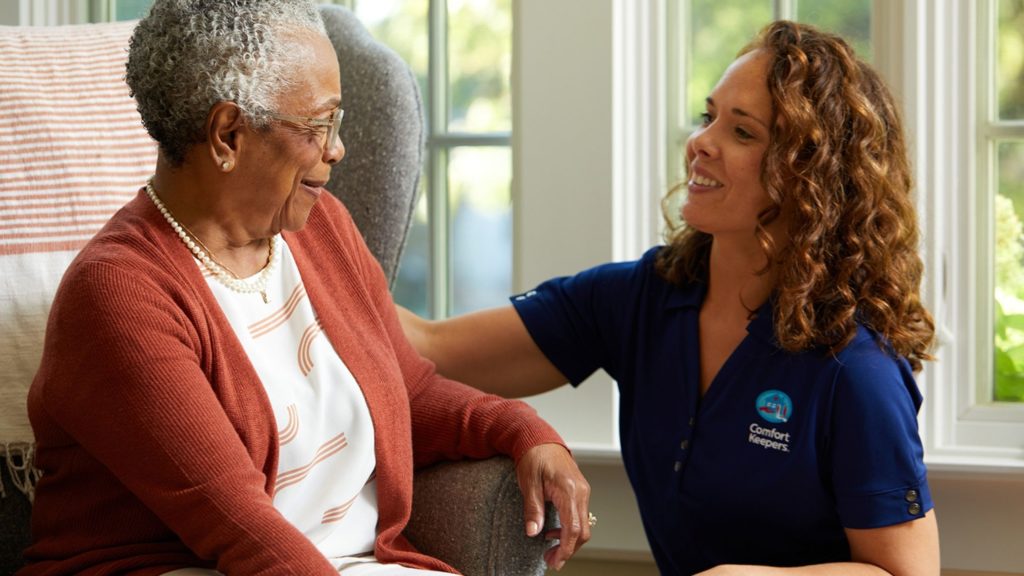 A senior woman looking fondly at a younger female caregiver wearing a Comfort Keepers shirt. 