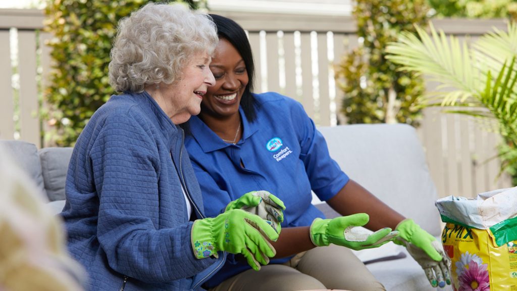 Comfort Keeper caregiver providing companionship care to a senior woman in the garden. 