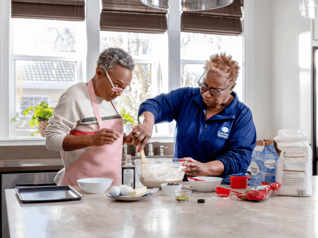 Senior woman in kitchen with caregiver baking | Preventing Unintentional Weight Loss in Seniors: Nurturing Health with Every Bite | Comfort Keepers Regina | BLOG POST