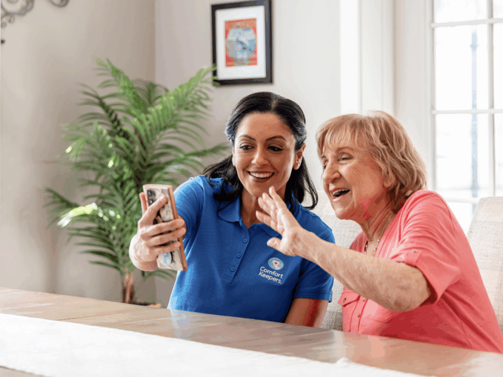 A senior woman with caregiver looking at smart phone | A Practical Guide to Adapting Activities for Seniors with Complex Health Needs | Comfort Keepers Ridge Meadows | BLOG POST