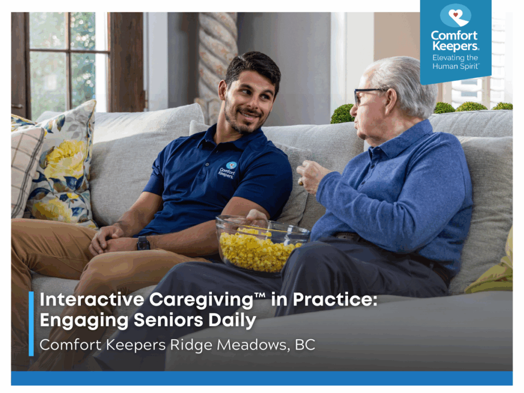 A senior male enjoys a bowl of popcorn while seated on couch with caregiver | Interactive Caregiving™ in Practice: Engaging Seniors Daily | Comfort Keepers Ridge Meadows