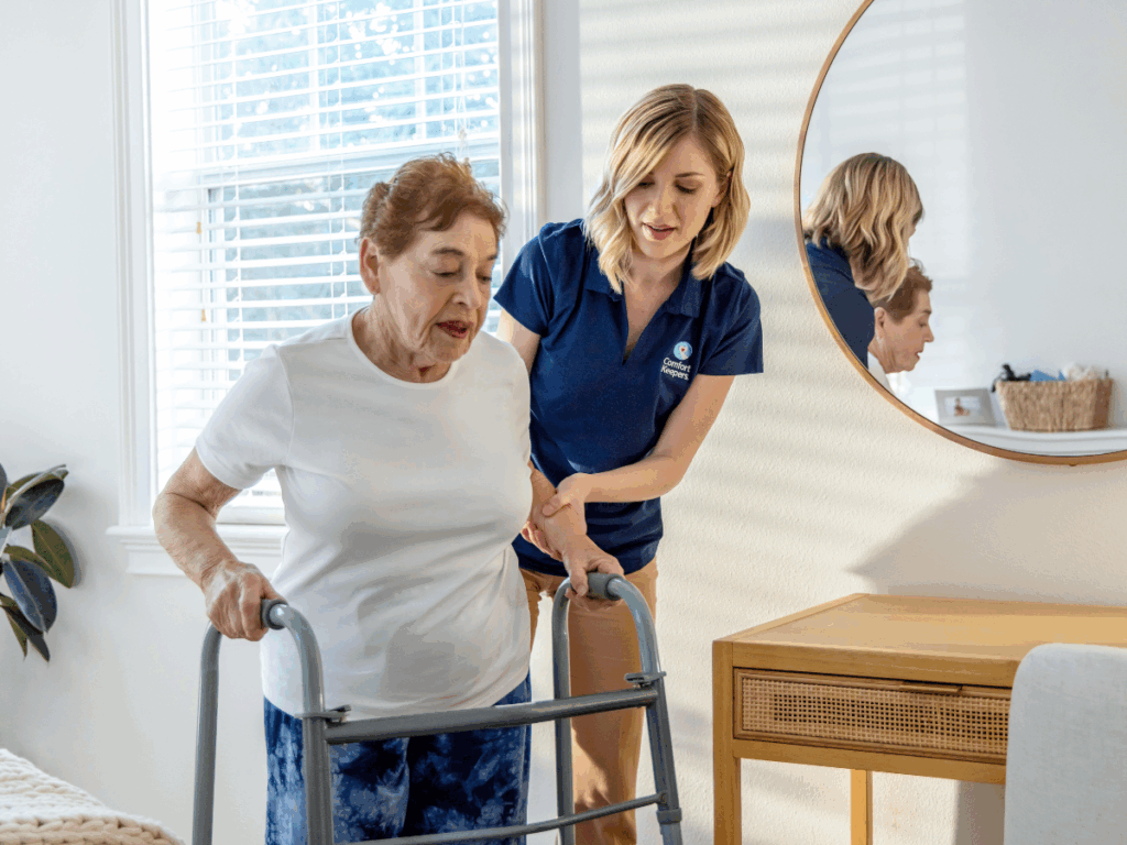 Senior woman using walker being assisted by caregiver | The Silent Struggle: Why General Caregiving Falls Short for Complex Needs | Comfort Keepers Tri-Cities | BLOG POST
