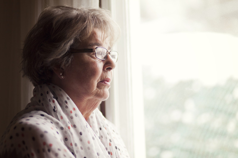 Senior women looking out window seemingly depressed | Loneliness and Depression | BLOG POST | Comfort Keepers Vancouver