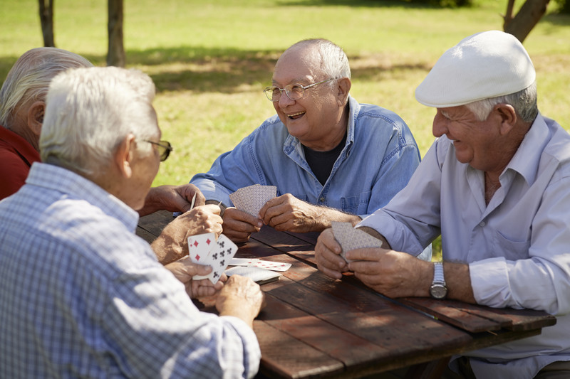 Seniors playing cards, laughing and gathered around picnic table | Seniors Socially Connected | Comfort Keepers Vancouver | BLOG POST