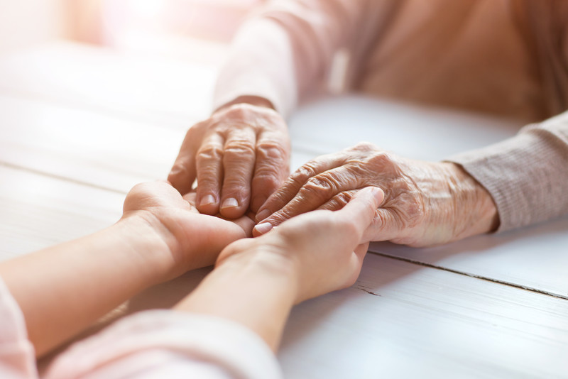 Two sets of hands grasped together atop a table | Senior Skin Health | BLOG POST | Comfort Keepers Vancouver