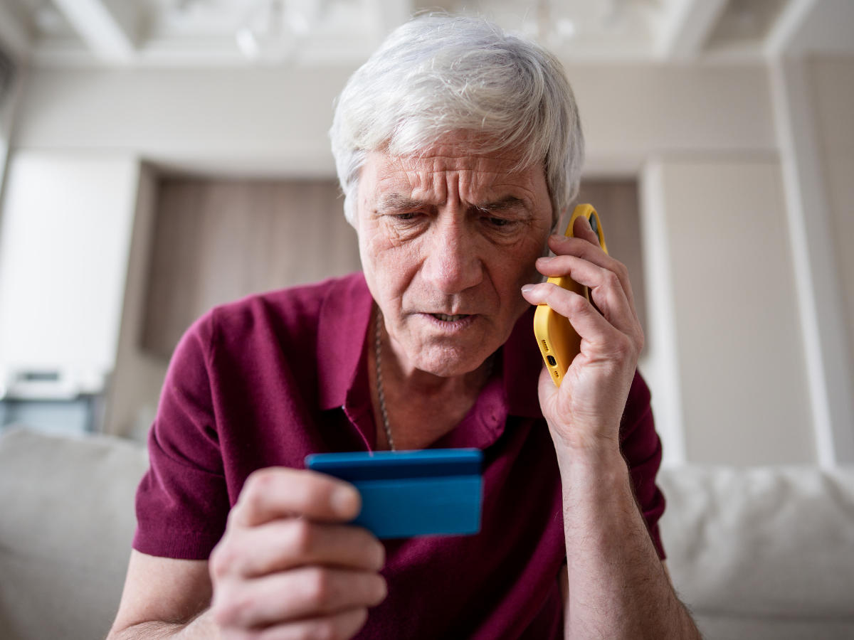 A senior male on the phone looking at his credit card | Preventing Cyber Fraud in Victoria's Seniors: 5 Useful Tips to Protect Your Loved One | Comfort Keepers Victoria