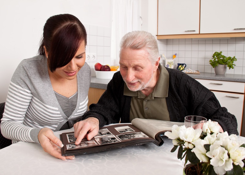 Senior looking at photos with caregiver | Alzheimer's In-Home Care | BLOG POST | Comfort Keepers Victoria