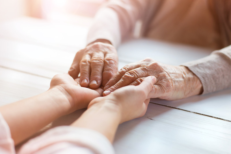 Two sets of hands being held across a table | Protect Senior Skin | BLOG POST | Comfort Keepers Victoria