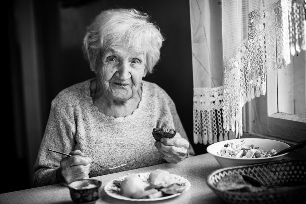 Senior seated at dinning table with a meal | Preventing Foodborne Illnesses | BLOG POST | Comfort Keepers Victoria