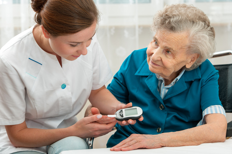 Senior woman checking blood sugar levels with caregiver | Seniors with Diabetes | BLOG POST | Comfort Keepers Victoria